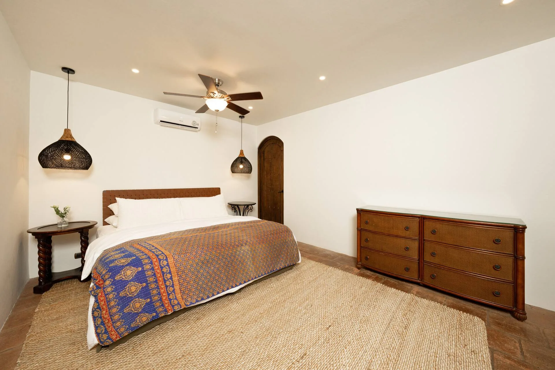 Bedroom with king bed, dresser, and pendant lighting